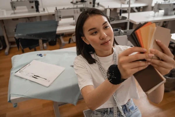 Diseñador asiático sosteniendo muestras de color borrosas en atelier - foto de stock