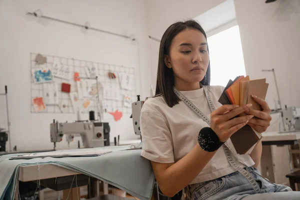 Young asian designer with tape measure holding color swatches — Stock Photo