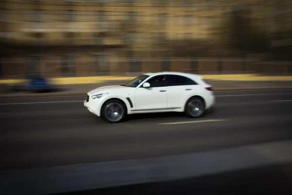 Bílé auto rychle jezdí po městě — Stock fotografie