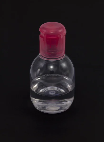 Botol plastik transparan dengan tutup merah di latar belakang gelap . — Stok Foto