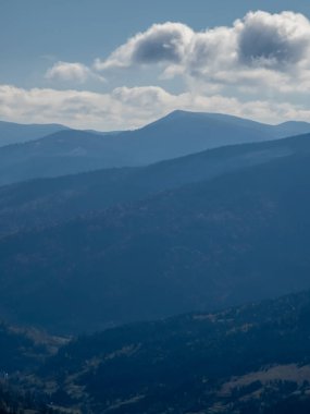Gökyüzünde bulutlar olan dağların dikey görüntüsü.