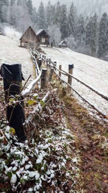 Karla kaplı eski bir ahşap evin dikey görüntüsü.