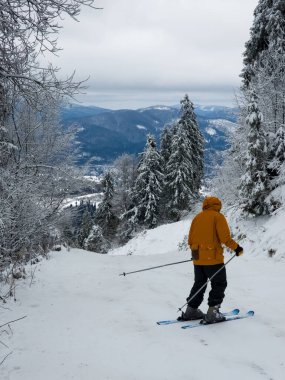 Kışın kayakçı tepeden aşağı kayıyor.