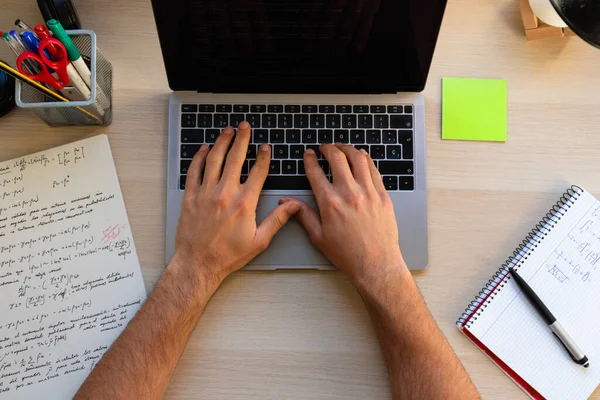 top view of high school or college student studying and typing on a laptop on a desk