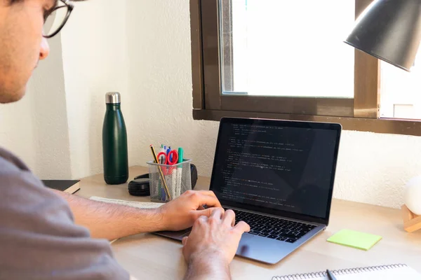 high school or college student studying and coding on a laptop on a desk
