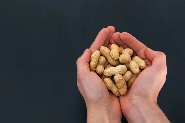 Elinde yer fıstığı tutan siyah bir arka plan ve kopyalama alanı olan biri.