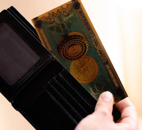 Kripto Bitcoin faturasını cüzdanından çıkaran adam kripto para birimini, yatırımı ve tasarruf konsepti fotoğrafını temsil ediyor.