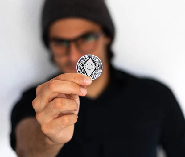 Şapkalı ve gözlüklü bir adam kripto ethereum 'u düşünüyor ve düşünüyor, kripto para birimini, yatırımı ve tasarruf konsepti fotoğrafını temsil ediyor.