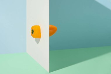 Beyaz duvardaki sarı biberler yeşil ve mavi arka planda izole edilmiş.