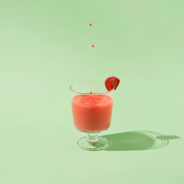 Sommar jordgubbsjuice med fallande droppar isolerad på en grön bakgrund. — Stockfoto