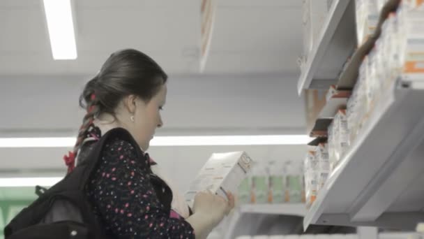 Menina loira em um supermercado escolhe comida infantil — Vídeo de Stock