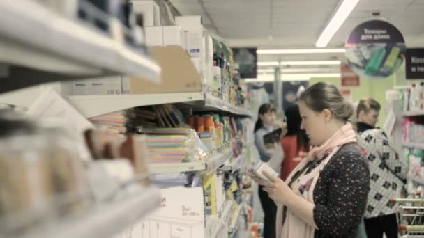 Blondes Mädchen trifft die Wahl in der Wirtschaftsabteilung des Supermarktes — Stockvideo