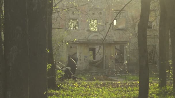 Mère marchant avec bébé dans une poussette près du bâtiment détruit — Video