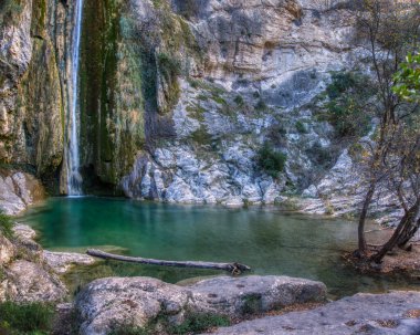 İspanya Castellon 'daki Villar şelalesinden kaynaklanan doğal havuz. Dağ kayalarıyla çevrili kristal berrak su havuzu ve ağaçların yanında.