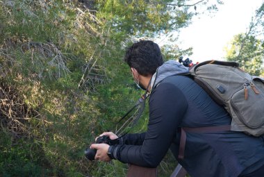 Çekici, koyu renk saçlı, orta yaşlı bir adam ahşap bir yolda doğanın tadını çıkarıyor. Doğadaki yüz maskesi. Açık hava, boş zaman ve kaçamak..