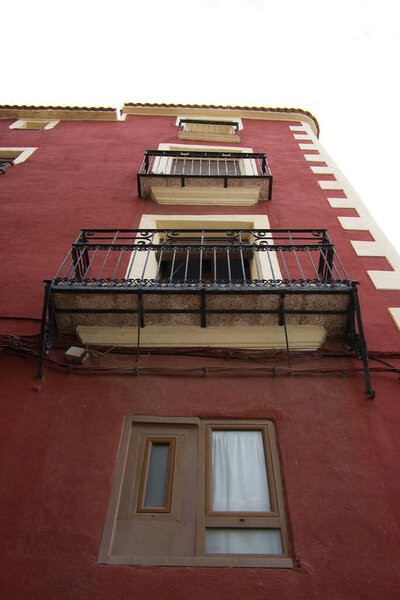 Image of a red building with balconies seen from below. Sky views