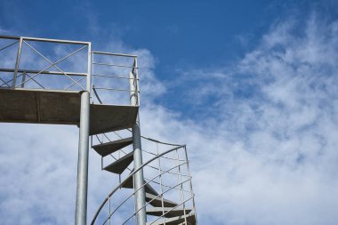 Mavi gökyüzü arka planında beyaz bulutlu metal spiral merdiven. Cennete gidiyorum. Başarılar, hedefler.