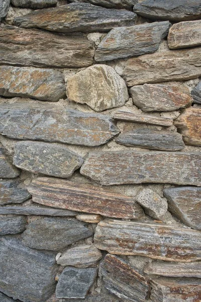 Wall of irregular stones aged in brown tones to be used as a background in advertisements for natural products. Vintage vertical background