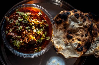 Biraz acı biber, soğan ve limonla servis tabağında tandır soslu Achari tavuğuyla birlikte..