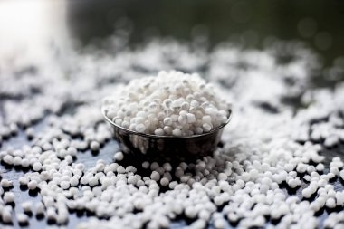 Siyah bir yüzey üzerinde cam bir tabakta çiğ sago incileri ya da tapyoka incileri yakın çekim.