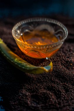 Parlayan deri için hardal tohumu maskesi. Hardal tohumu, aloe vera ve siyah bir yüzey üzerinde cam bir kasede biraz bal içeren yüz maskesi malzemeleri..