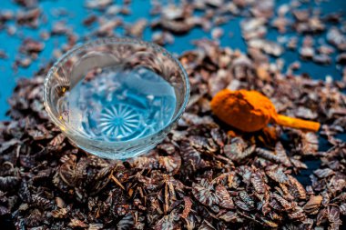 Supari ya da betel fındığı içeren pürüzsüz cilt maskesi ve siyah ahşap bir yüzey üzerinde biraz zerdeçal tozu ve su..