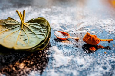 Siyah ahşap bir yüzey üzerinde betel yaprakları, zerdeçal ve tuz içeren ekşi boğaz için Ayurvedic ilaç.