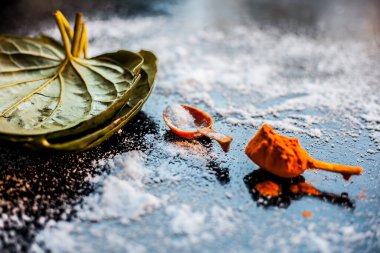 Siyah ahşap bir yüzey üzerinde betel yaprakları, zerdeçal ve tuz içeren ekşi boğaz için Ayurvedic ilaç.