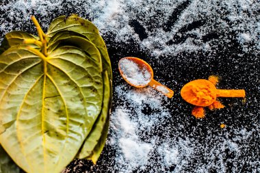 Siyah ahşap bir yüzey üzerinde betel yaprakları, zerdeçal ve tuz içeren ekşi boğaz için Ayurvedic ilaç.