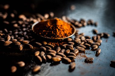 Siyah bir yüzeye çiğ kahve çekirdeği ve pudra..