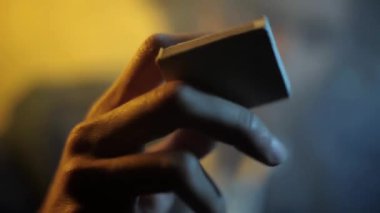 Beyaz renkli kibrit kutusuyla oynayan bir adamı yakından çek. Bir kibrit kutusu çalan / gösteren adam.