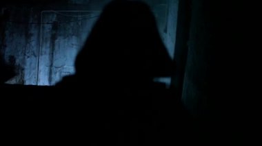 Dramatik ışıklandırmada uzun siyah bir ceket giyen bir kadının alt kata taşınması..