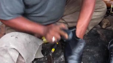 Yol kenarındaki ayakkabı tamircisinin, deri ayakkabıları cilalarken....