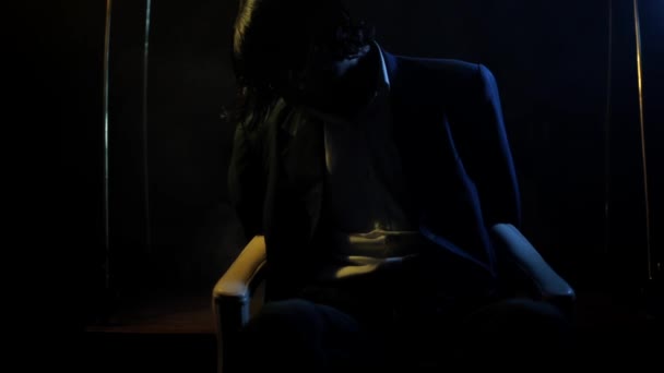 一个商人坐在椅子上 椅子上闪烁着戏剧性的光芒 一些浓烟从镜框底部高清晰地冒了出来 — 图库视频影像