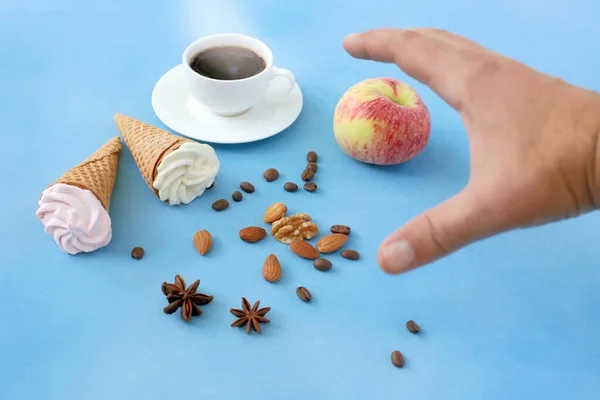 The hand reaches for the cup. Food and drink on a blue background.