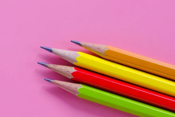 Colored pencils for drawing and painting on a pink background.