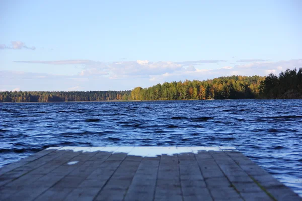 O fim do cais de madeira e água azul do lago — Fotografia de Stock