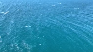 Yukarıdan deniz manzarası, mavi renk, su hareketi, beyaz deniz tarakları, büyüleyici video.