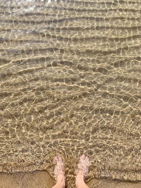 ชายหาดท นทรายส เหล องต งอย าระลอกคล นเท าบนขอบว นหย — ภาพถ่ายสต็อก