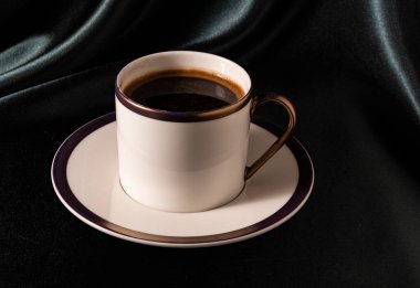 Yeşil arka planda beyaz bardakta sade kahve.