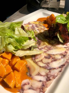 Ahtapot carpaccio tatlı patates ve salata ile servis edilir.