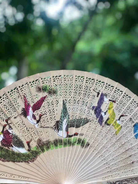 Handmade wooden folding fan with painted birds in Mandalay, Myanmar