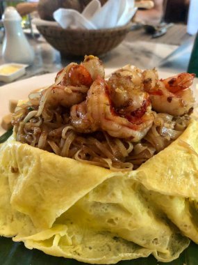 Lezzetli karidesler Tayland erişteleri yumurta kaplı tabakta servis edilir.