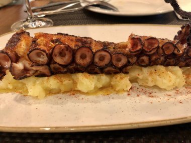 Patates püresiyle servis edilen kırmızı biberli ahtapot dokunaçları.