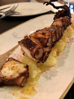 Patates püresiyle servis edilen kırmızı biberli ahtapot dokunaçları.