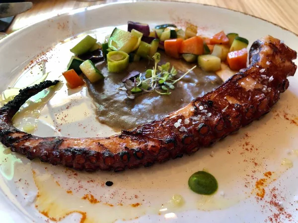 Izgara İspanyol ahtapot dokunaçları, sebzelerle servis edilir.