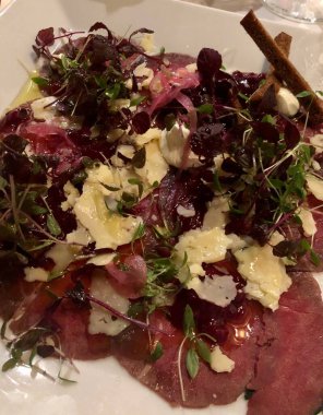 Parmesan peyniri ve otla servis edilen taze etli carpaccio.