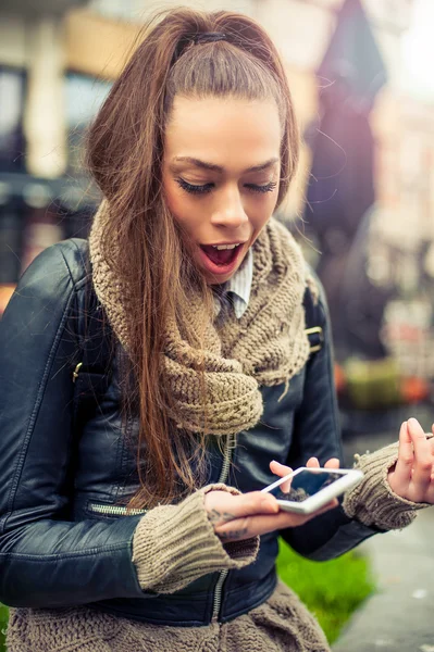 Uśmiechnięta młoda kobieta przy użyciu mobilnych na ulicy — Zdjęcie stockowe