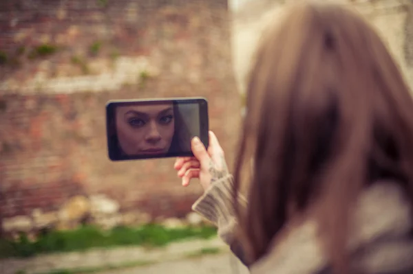 Frau spiegelt sich auf dem Bildschirm ihres Handys — Stockfoto