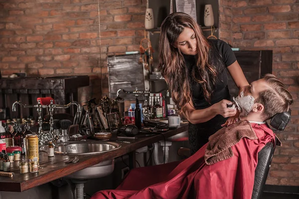 Парикмахерша бреет клиента в парикмахерской — стоковое фото